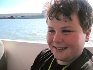 Happy Leo riding an amphibious vehicle, with the  San Francisco Bay in the background