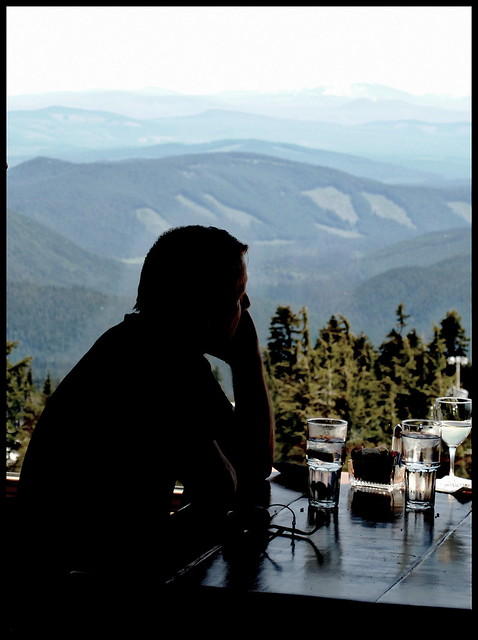 a guest looks out over the Cascade Mountain range from the Ram's Head Bar, third floor of the Timberline Lodge