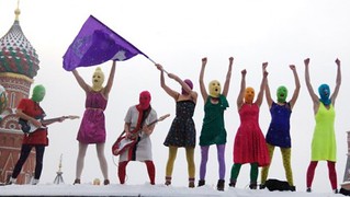 the members of pussy riot standing on a wall wearing bright balaclavas
