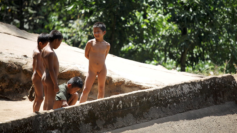 苗族部落小男孩光著屁股在池邊玩耍，偶爾跳入池塘降暑