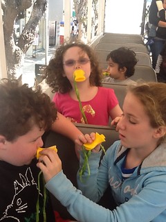 image: My three kids using yellow "quacker" whistles. Leo's sister is helping him with his.