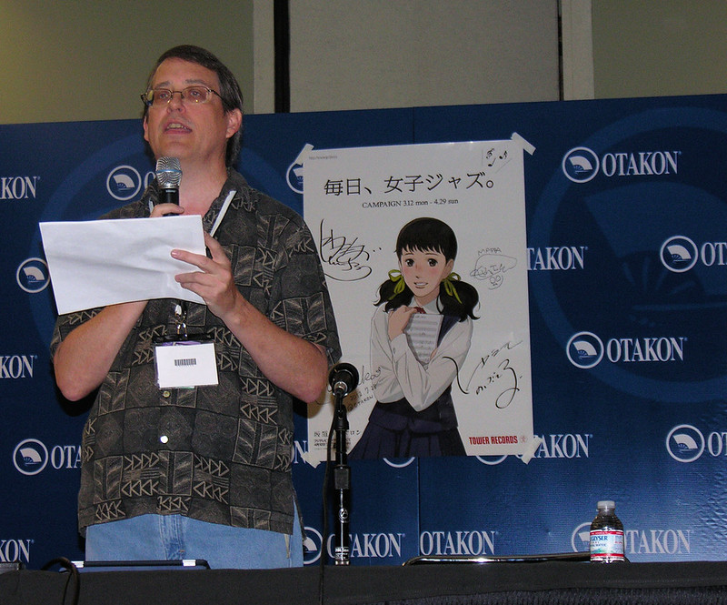 David Williams goes over the latest titles from Sentai Filmworks in front of a signed poster from Kids on the Slope (licensed by Sentai)
