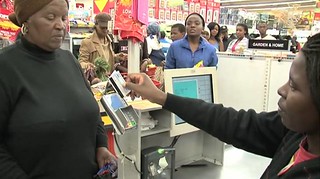 A SASSA grant recipient using her new SASSA Debit MasterCard card at point of sale to pay for her groceries