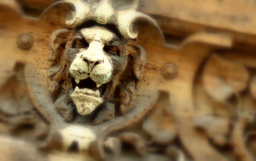 An intense lion on a building off of a side street.