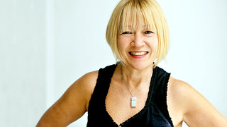Smiling white woman in black tank top against white background.