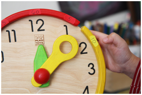 Teaching kids to tell time with the wooden Plan Toys Activity Clock