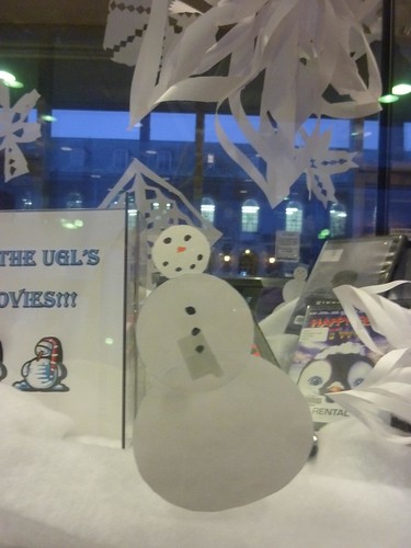 A paper snowman greets you from a glass display case.