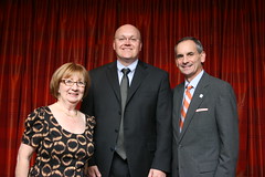 Ruth Crocker and Christopher B. Roberts pose in front of a red curtain.