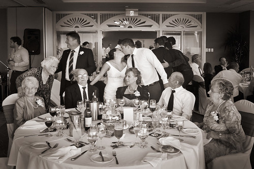 Bride and groom kissing amongst guests.