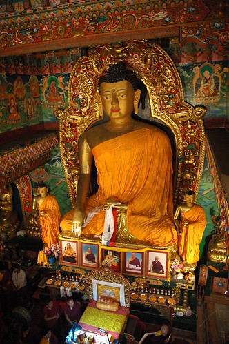 Statue of Lord Buddha with chief students, His Holiness Jigdal Dagchen Sakya climbs down from his throne, photos of renown lamas, bowls of nectar offerings with marigolds, lights, aura, Sakya lineage lords, monks, Tharlam Monastery, Boudha, Nepal by Wonderlane