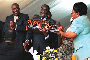 President Mugabe is helped by Vice-President Mujuru to receive a gift from Mwana Africa’s Chief Executive Mr Kalaa Mpinga while Youth Development, Indigenisation, and Economic Empowerment Minister Saviour Kasukuwere looks on at the Bindura Community. by Pan-African News Wire File Photos