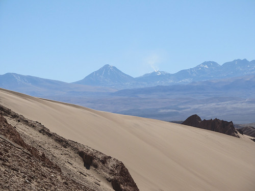 Le désert d'Atacama: vue sur des volcans enneigés et dont un fume depuis la Vallée de la Mort
