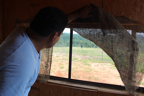 Variano Suarez peers from a deer stand into a field. Suarez purchased the land for recreational activities, like fishing, hunting and relaxing in nature.