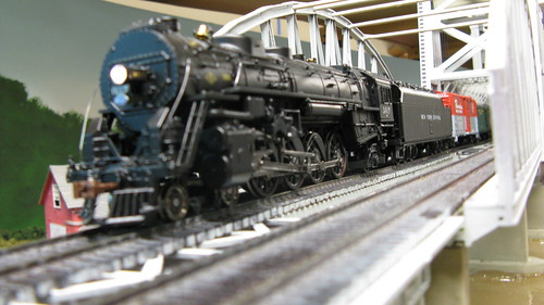 An MTH model of a New York Central 4-8-2 Mohawk class steam locomotive exits the Missisippi River bridge with a passenger train in tow. by Eddie from Chicago