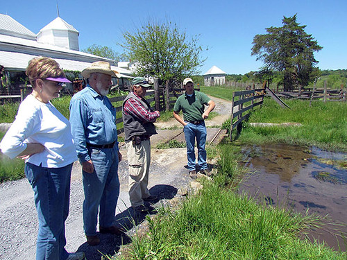 Peyton and Myra Yancey look at streambank vegetation with NRCS Soil Conservation Technician Mike Phillips while District Conservationist Cory Guilliams discusses water quality benefits of installed practices.