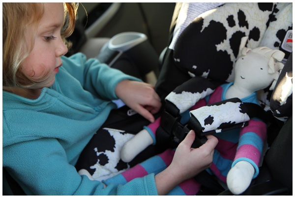 Preparing for baby: practicing strapping her baby doll into the infant car seat