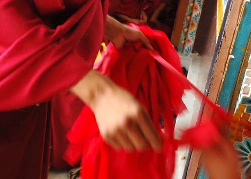 Wearing maroon robes, a Tibetan Buddhist monk hands out red ritual blindfolds for the initiation, Sakya Lamdre, Tharlam Monastery of Tibetan Buddhism, Boudha, Kathmandu, Nepal by Wonderlane