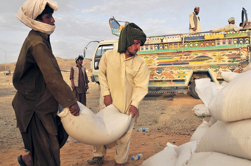 Two Afghan truck drivers stack bags of grain in Shorabak, Afghanistan
