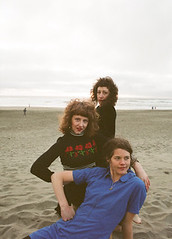 the three members of Grass Widow sitting together on the beach