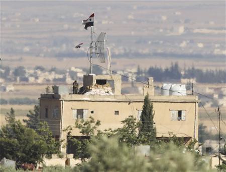 A Syrian solidier stands atop of building as seen from the border with Turkey. Fighting continued on July 2, 2012 in the suburbs surrounding Dasmascus the capital of the Middle Eastern state. by Pan-African News Wire File Photos