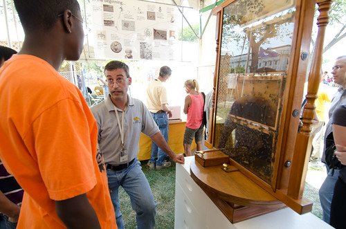  Agricultural Research Service Biological Technician Andrew Ulsamer talks to a visiting student about the live bee colony display at a tent devoted to bee research and honey production at 2012 Smithsonian Folklife Festival, on Thursday, June 28, 2012 on the National Mall in Washington, D.C.  One of the three themes this year is “Campus and Community.” It celebrates the 150 years of the USDA and the Land-Grant University System. The U.S. Department of Agriculture (USDA) and the Land-Grant system extend education across the country, contributing to American agriculture success and rural prosperity. “Campus and Community” has demonstrations, discussions, hands-on activities, and entertainment to that showcase the many ways that this partnership works to improve American agriculture and rural life.  USDA photo by Lance Cheung.