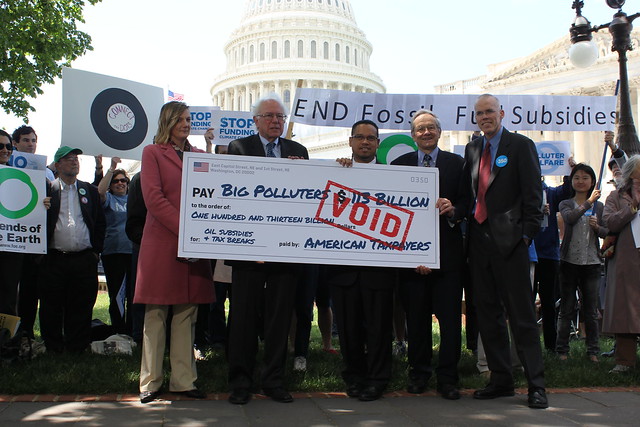 Rally speakers hold up the fossil fuel industry's voided check