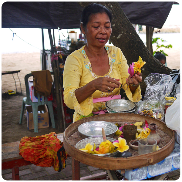 Balinese woman crafting flower offerings