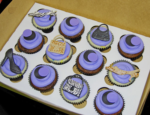 purple and black birthday cupcakes topped with shoes and purses