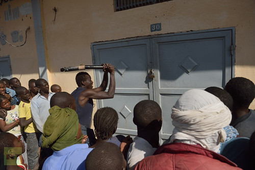 A Malian tries to break the lock off a store front as looters and residents stand by in the streets of Timbuktu on January 29, 2013. by Pan-African News Wire File Photos