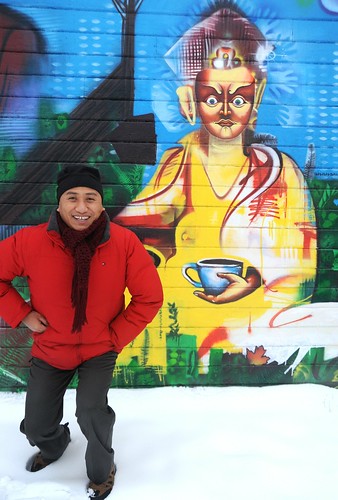 Lama Rabten Tshering kneels near Padmasambhava with coffee, Guru Rinpoche wall mural, Lama Rabten is a Spiritual Director of Nalandabodhi Foundation (Vancouver BC Canada), Lama G's Cafe, Fremont, Seattle, Washington, USA by Wonderlane