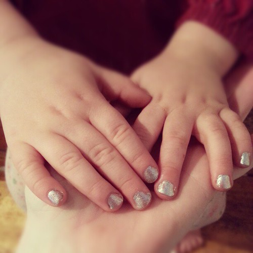 Silver bells Christmas nails on pudgy two year old fingers.