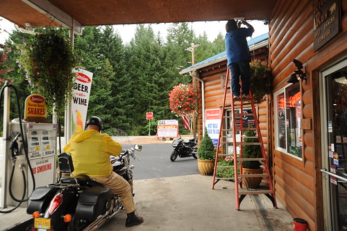 Countryside gas station, biker setting up to leave, working on a ladder, log siding, turnoff to Breightenbush, Detroit Lake, Marion County, Oregon, USA by Wonderlane