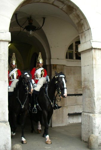 Changing of the guard, riding through the arch, British soldiers mounted on horseback, red coats, metal hats, white saddle cloth, London, England, UK by Wonderlane
