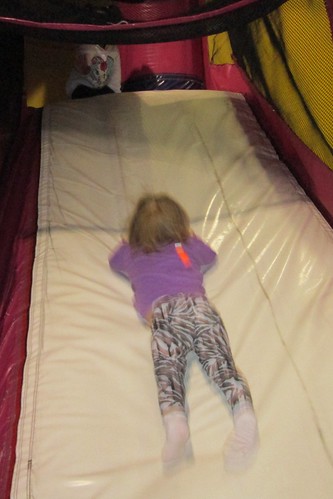 Lucy has her own unique way of doing the slide at the bounce house.