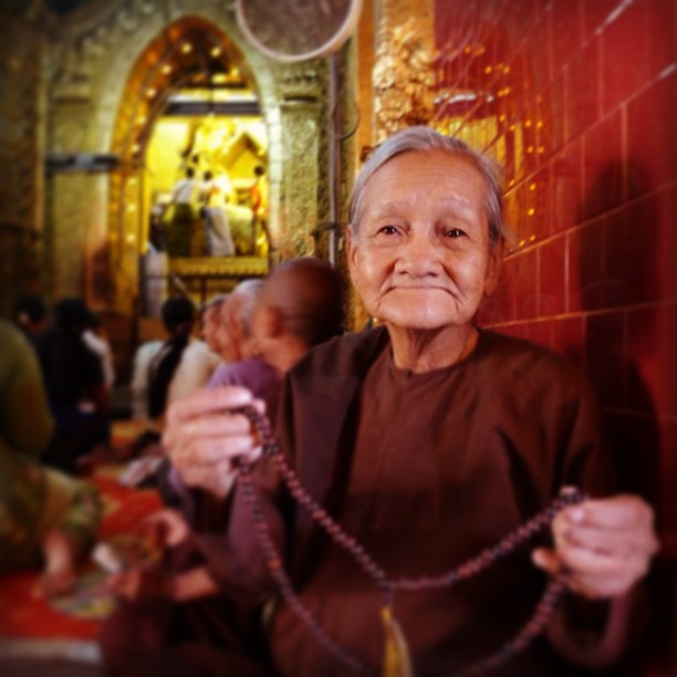 An old lady at the #Mahamuni Pagoda, where men adorn the #Buddha statue with gold leafs, while women watch it on the big TV screen and pray...