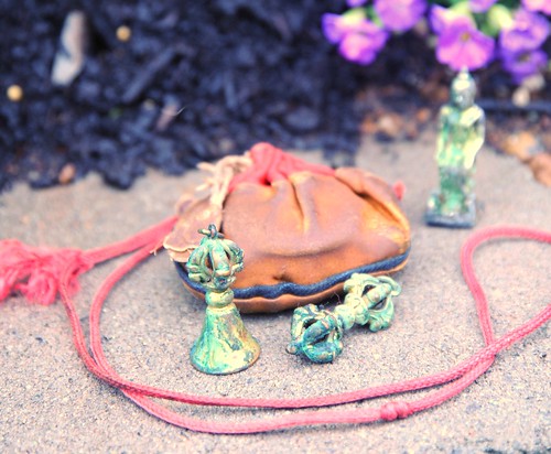 Contents of an old Tibetan Buddhist blessing bag, dorje, bell, statue of Maitreya, the Buddha of the future seated, blessing cord, bag, Garden for the Buddha, Seattle, Washington, USA by Wonderlane