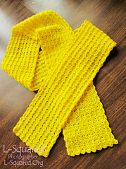 Completed yellow petal scarf laying on a wooden surface.