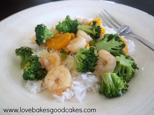 Orange and Broccoli Shrimp with Rice on white plate with fork.