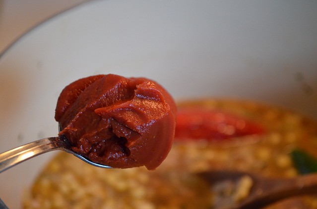 adding tomato paste to black bean soup