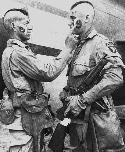 This photo of paratroopers Clarence C. Ware and Charles R. Plaudo painting each other's faces on the afternoon of June 5, 1944, was printed in Stars and Stripes, and helped form the legend of "The Filthy Thirteen."