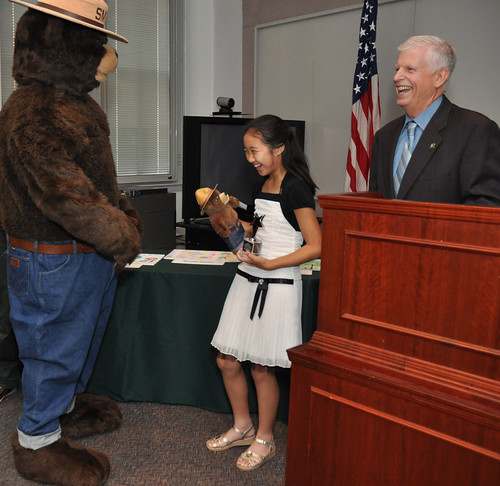Smokey Bear presents Caroline Tan, 11, with a replica of himself during a ceremony led by U.S. Forest Service Chief Tom Tidwell to honor the Westfield, N.J., girl as the national winner in the 2012 Smokey Bear & Woodsy Owl Poster Contest. Caroline’s winning poster was chosen from nearly 22,000 entries. Dominic Cumberland/U.S. Forest Service Photo