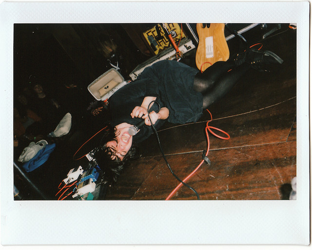 marissa paternoster from screaming females on the floor of a wooden stage with her microphone screaming into it