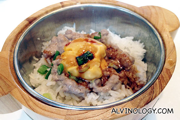 Rice served in a small wood pot with salted egg and minced meat