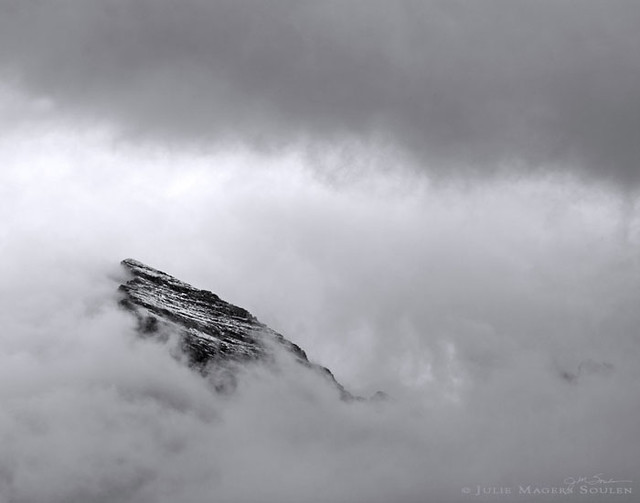 Colorado mountain in clouds photo, of a rugged peak punching a hole through the cloud filled sky. Maroon Bells, Colorado