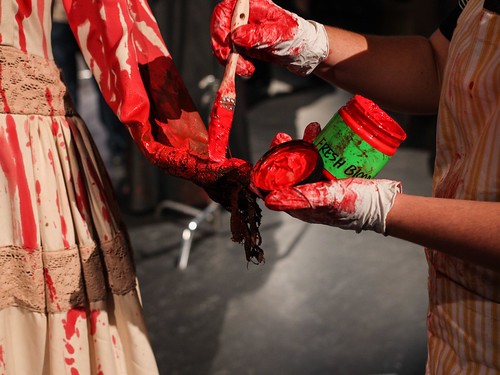 Costumer applying fresh blood paint color to dress