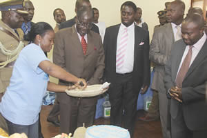 President Mugabe watches as Harare Polytechnic student Elizabeth Rubaya cuts a cake made from the masau fruit (Ziziphus Mauritiana) for him at the Research and Intellectual Exposition at the University of Zimbabwe September 6, 2012. by Pan-African News Wire File Photos