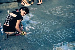 Occupier draws with chalk on sidewalk during anniversary protest