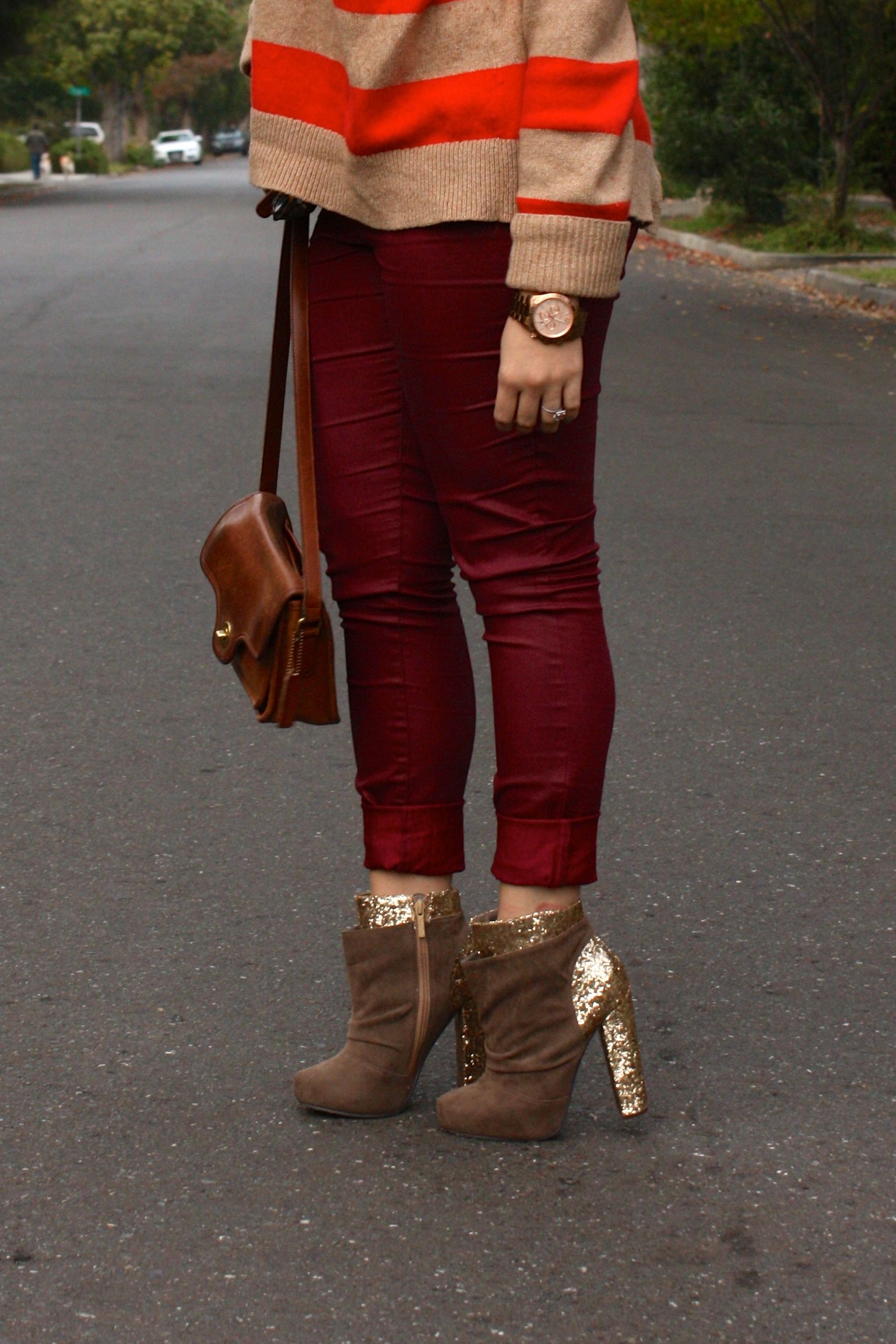 burgundy waxed jeans with orange striped sweater and brown coach bag plus glitter booties