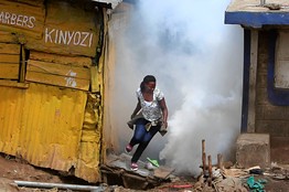 A woman runs to escape teargas in Kenya during clashes with ethnic Somalians. Tensions have escalated since the invasion of Somalia by the Kenyan Defense Forces. by Pan-African News Wire File Photos