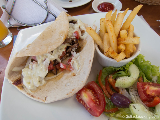Giro with pork, in pita bread, topped with tomato, onion, and tzatziki (cucumber-garlic sauce), service with fries and salad